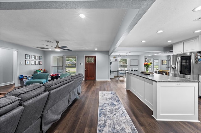 living room with a textured ceiling, baseboards, dark wood-style flooring, and recessed lighting