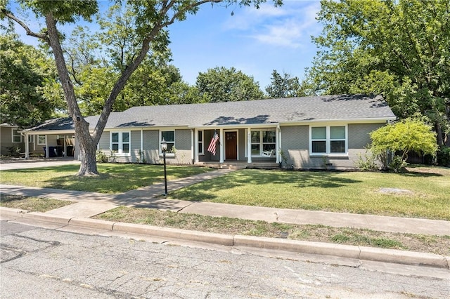 ranch-style house featuring brick siding, covered porch, a carport, and a front yard