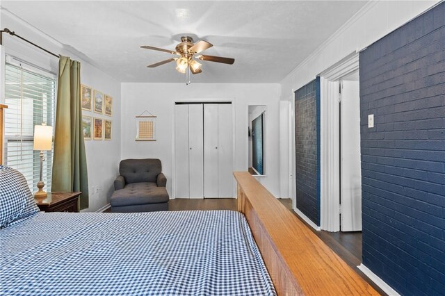 bedroom featuring ceiling fan, brick wall, a closet, and wood finished floors