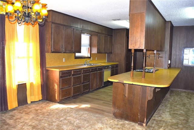 kitchen with wood walls, kitchen peninsula, a breakfast bar area, a notable chandelier, and a textured ceiling