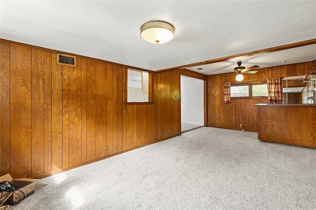 unfurnished living room with light colored carpet, ceiling fan, and wooden walls