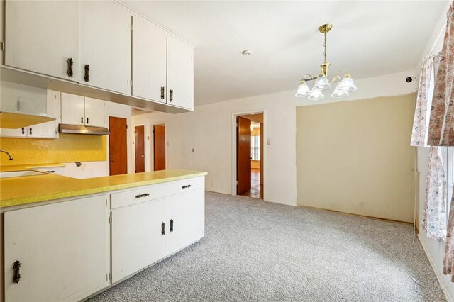 kitchen with white cabinets, pendant lighting, light carpet, and a notable chandelier