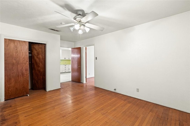 unfurnished bedroom with hardwood / wood-style flooring, ceiling fan, and a closet