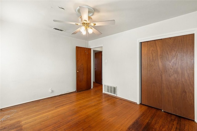 unfurnished bedroom with ceiling fan, dark wood-type flooring, and a closet