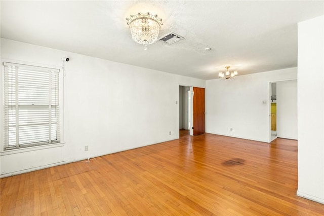 empty room featuring hardwood / wood-style floors and a notable chandelier