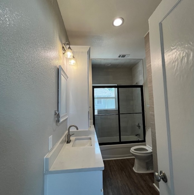 full bathroom with wood-type flooring, vanity, toilet, and enclosed tub / shower combo