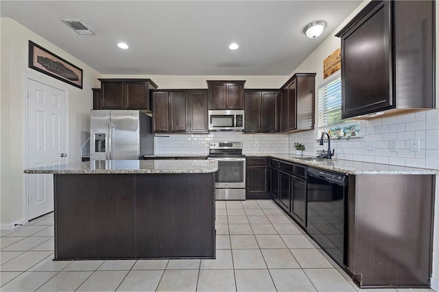 kitchen featuring light stone countertops, sink, stainless steel appliances, light tile patterned floors, and a kitchen island