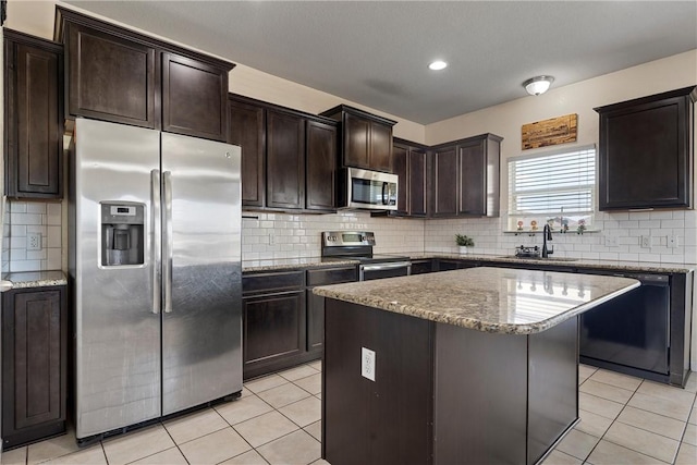 kitchen with a kitchen island, sink, light tile patterned floors, and stainless steel appliances