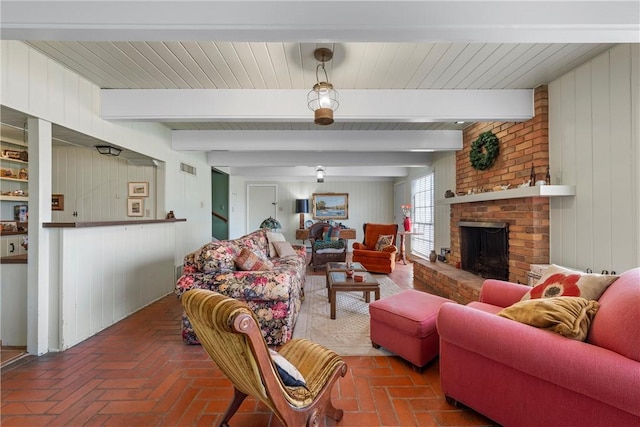 living room with beam ceiling, a fireplace, brick floor, and visible vents