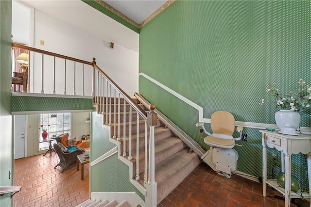 stairs featuring brick floor, a towering ceiling, and crown molding