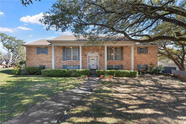 raised ranch with brick siding and a front yard