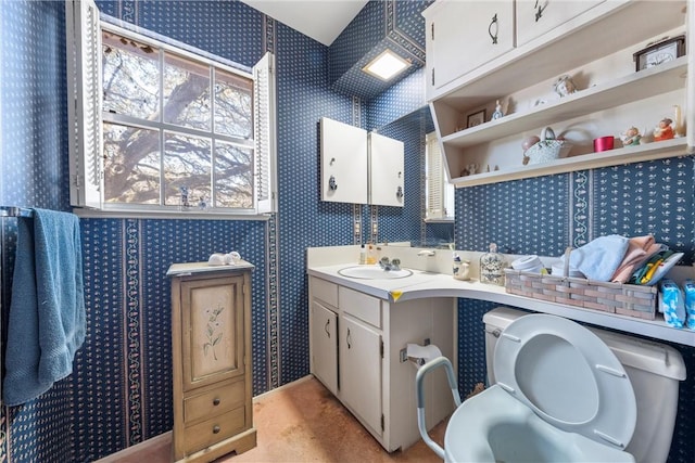 bathroom featuring toilet, vanity, and wallpapered walls