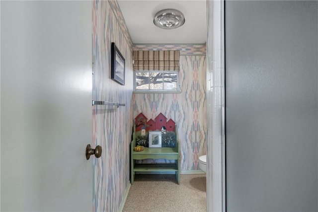 bathroom featuring baseboards, toilet, and wallpapered walls