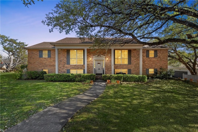 split foyer home with brick siding and a lawn