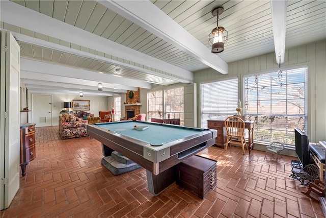 playroom featuring beamed ceiling, pool table, brick floor, and a brick fireplace