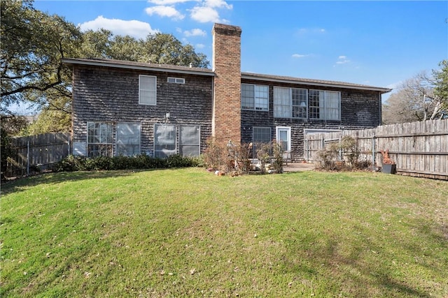 rear view of property with a fenced backyard, a chimney, and a yard