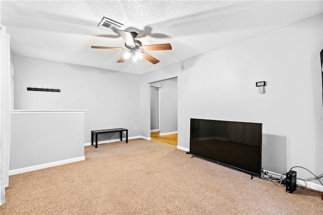 interior space featuring ceiling fan, light carpet, and a textured ceiling