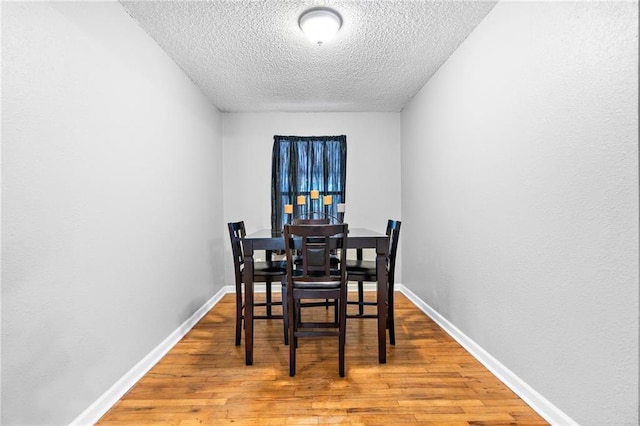 dining space featuring hardwood / wood-style flooring and a textured ceiling