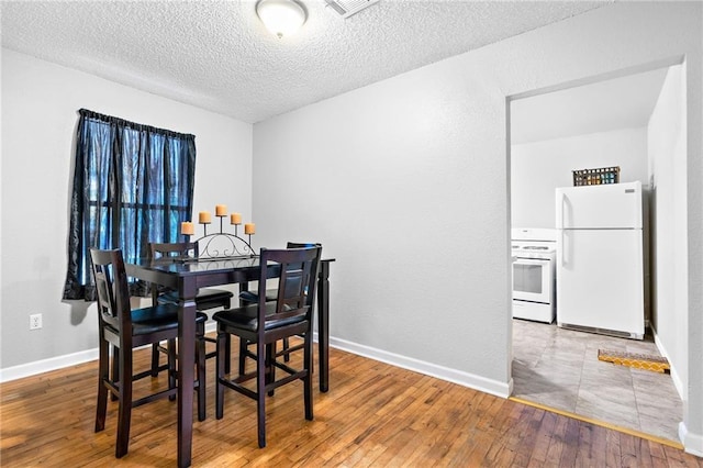 dining area with wood-type flooring and a textured ceiling