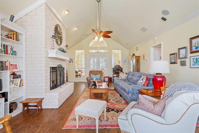 living room with dark wood-type flooring, crown molding, vaulted ceiling, a brick fireplace, and ceiling fan