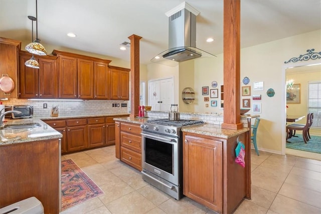 kitchen featuring sink, high end stove, island exhaust hood, kitchen peninsula, and pendant lighting