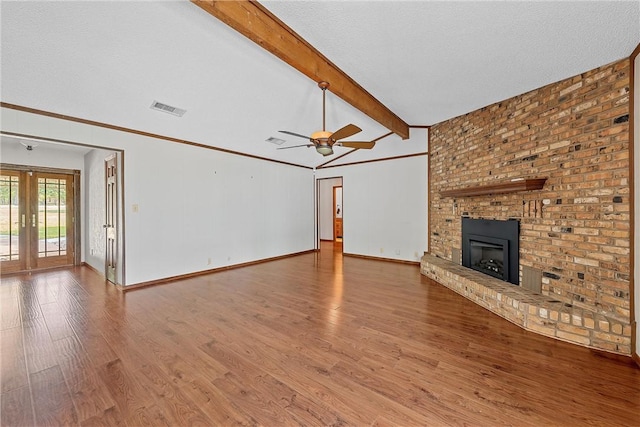 unfurnished living room with french doors, a textured ceiling, lofted ceiling with beams, hardwood / wood-style flooring, and a fireplace