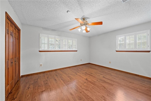 unfurnished bedroom with hardwood / wood-style floors, a textured ceiling, a closet, and ceiling fan