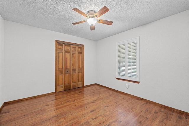 unfurnished bedroom with a closet, ceiling fan, hardwood / wood-style floors, and a textured ceiling