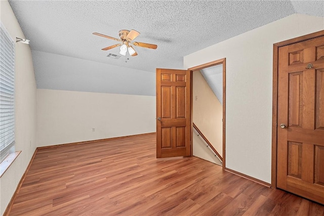 bonus room with a textured ceiling, ceiling fan, light hardwood / wood-style floors, and vaulted ceiling