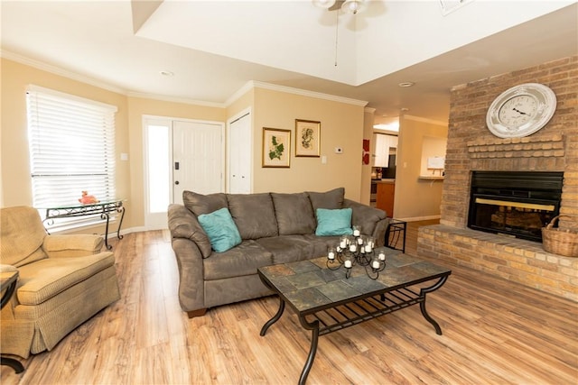 living area with a brick fireplace, crown molding, baseboards, and wood finished floors