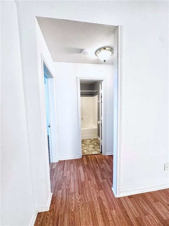 hallway with hardwood / wood-style flooring and a textured ceiling