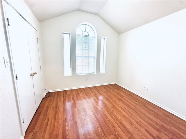 unfurnished bedroom with lofted ceiling and hardwood / wood-style floors