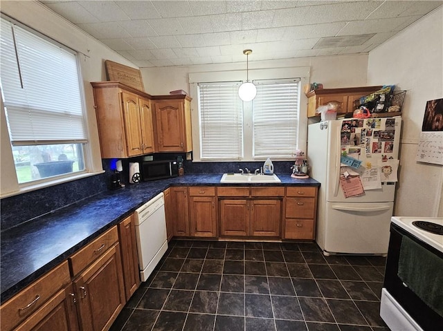 kitchen with sink, white appliances, and decorative light fixtures