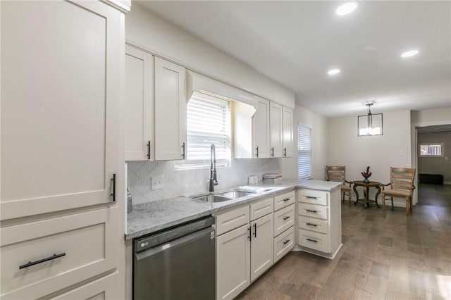 kitchen with dark wood-type flooring, sink, stainless steel dishwasher, white cabinetry, and kitchen peninsula