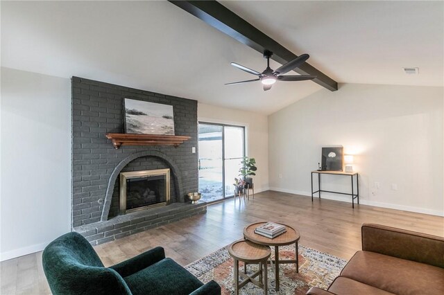 living room featuring vaulted ceiling with beams, ceiling fan, hardwood / wood-style floors, and a brick fireplace