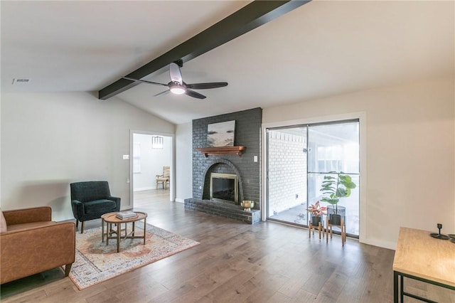 living room featuring a fireplace, wood-type flooring, vaulted ceiling with beams, and ceiling fan