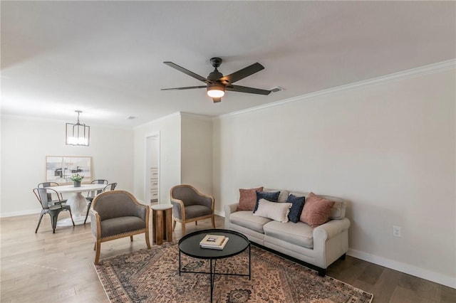 living room featuring ornamental molding, ceiling fan with notable chandelier, and light wood-type flooring