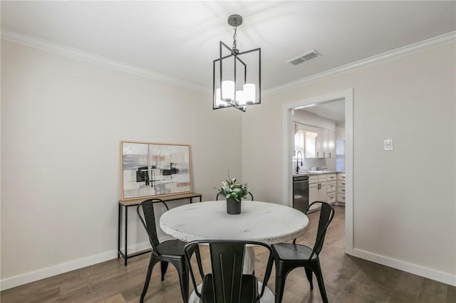 dining room with crown molding, sink, dark wood-type flooring, and an inviting chandelier