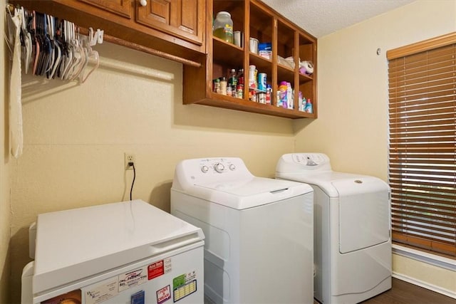 clothes washing area featuring washer and clothes dryer, dark hardwood / wood-style flooring, cabinets, and a textured ceiling