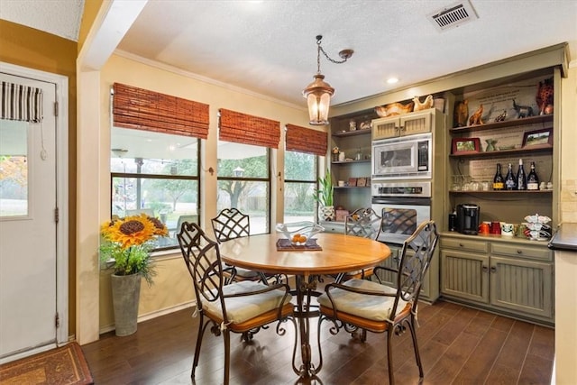 dining room with dark hardwood / wood-style floors, ornamental molding, and a textured ceiling