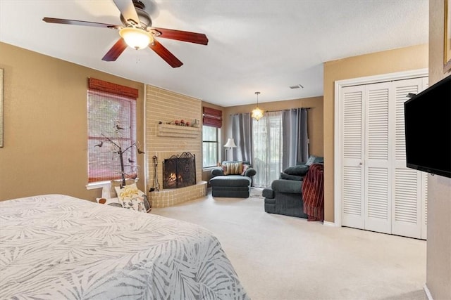 carpeted bedroom featuring ceiling fan, a fireplace, and a closet