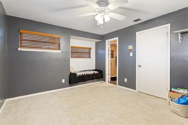 unfurnished bedroom with a textured ceiling, ceiling fan, and light carpet