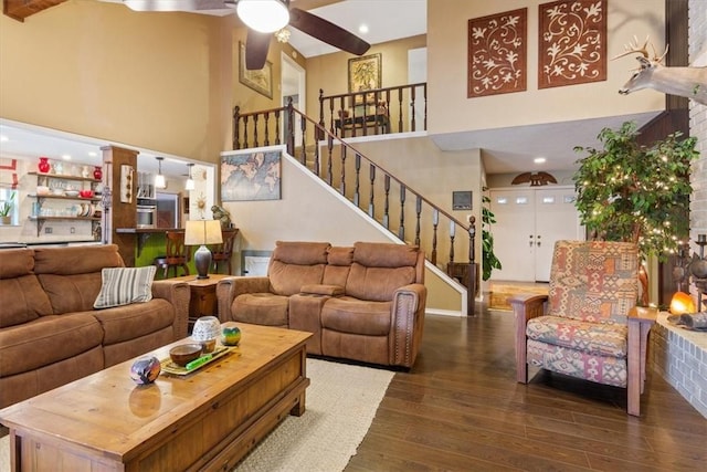 living room with a high ceiling, ceiling fan, dark wood-type flooring, and beam ceiling