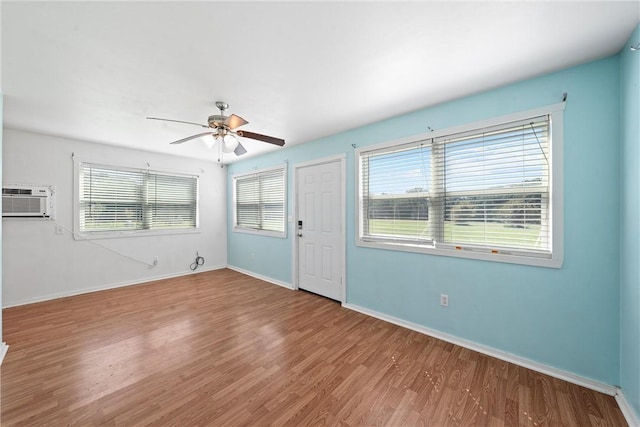 unfurnished room with hardwood / wood-style floors, a wall unit AC, and ceiling fan