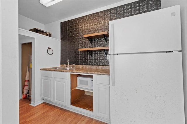 kitchen with white cabinetry, sink, tasteful backsplash, light hardwood / wood-style flooring, and white appliances