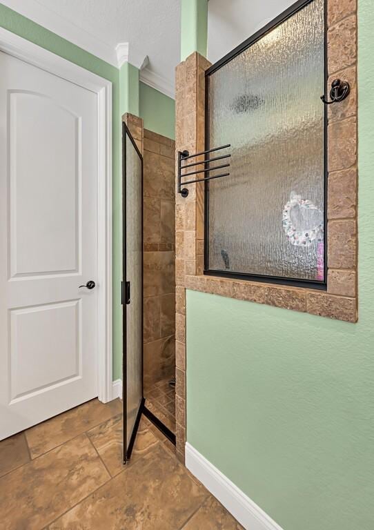 bathroom with crown molding, tile patterned flooring, and tiled shower