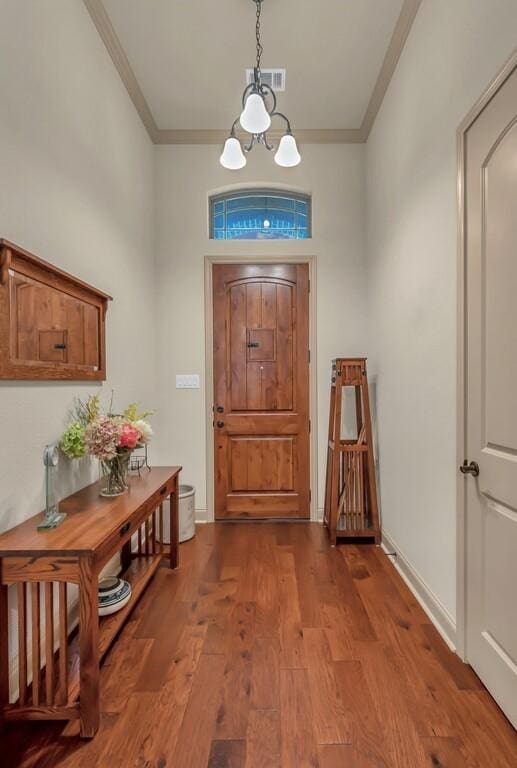 entrance foyer with hardwood / wood-style flooring, an inviting chandelier, and ornamental molding