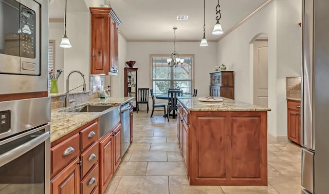 kitchen featuring light stone countertops, stainless steel appliances, decorative light fixtures, an inviting chandelier, and a center island