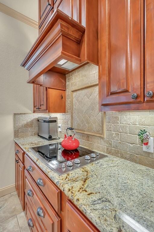 kitchen with premium range hood, decorative backsplash, light stone countertops, and stainless steel gas stovetop