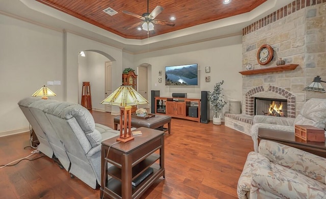 living room featuring hardwood / wood-style flooring, a raised ceiling, a stone fireplace, and wood ceiling